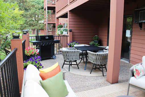 A patio with a table and chairs and a grill.