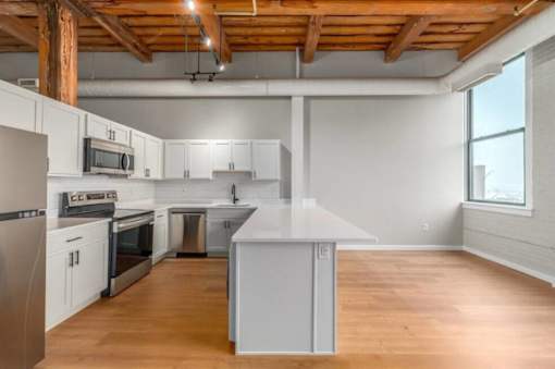 A kitchen with wooden floors and white cabinets.