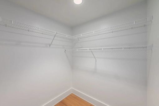 Empty white walk in closet with shelves.