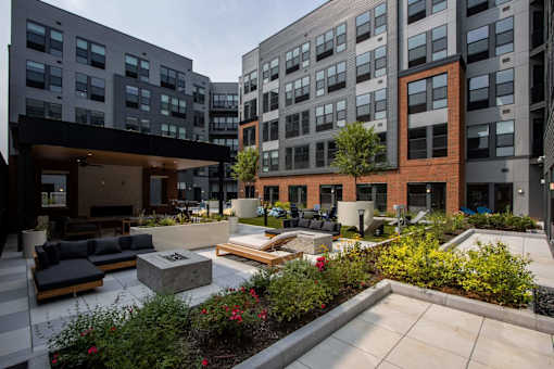 A courtyard with a fireplace and seating area surrounded by buildings.