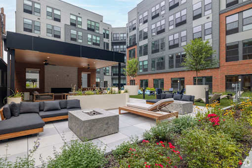 A modern outdoor seating area with a fireplace and a variety of plants.