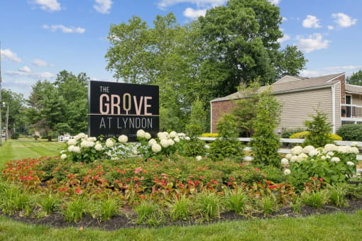 the grove apartments sign in front of flowers and plants at The Grove at Lyndon, Louisville