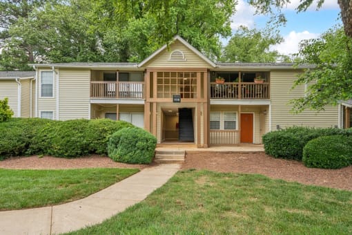 a yellow house with a sidewalk in front of a yard at Clarion Crossing Apartments, PRG Real Estate Management, Raleigh