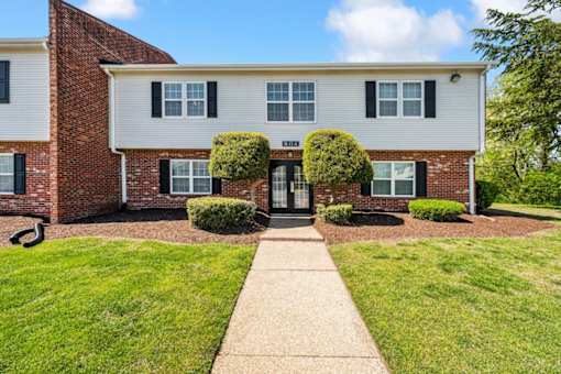 A white and brick building with a green lawn in front at Rivers Landing Apartments, Virginia, 23666
