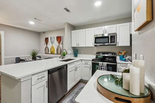 A modern kitchen with white cabinets and stainless steel appliances.
