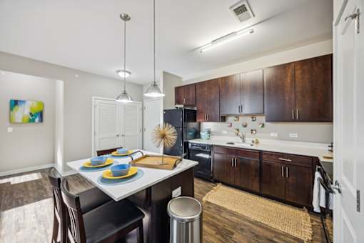 A modern kitchen with dark wood cabinets and a white island. at AMP Apartments, Kentucky, 40206