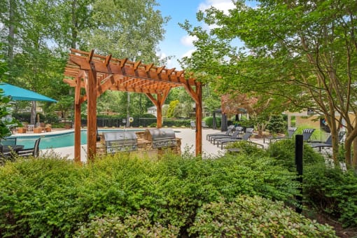 a patio with a wooden pergola and a swimming pool at Clarion Crossing Apartments, PRG Real Estate Management, Raleigh