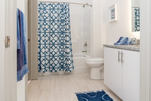 a bathroom with a white toilet and a blue shower curtain  at The Point on 38th, Norfolk