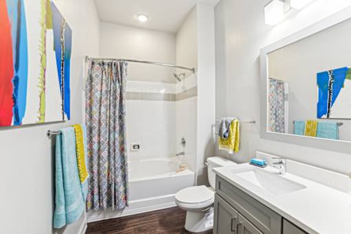 A bathroom with a white toilet, a white sink, and a white bathtub with a shower curtain at Proximity Apartments, South Carolina, 29414