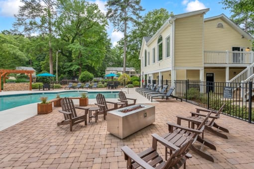 a backyard with a pool and patio with chairs and umbrellas at Clarion Crossing Apartments, PRG Real Estate Management, Raleigh