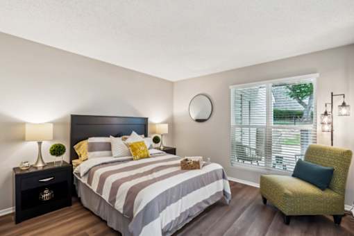 A bedroom with a large bed and a green chair.