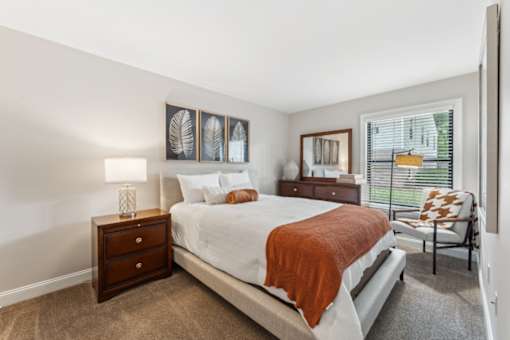 A bedroom with a bed, nightstand, and chair.
