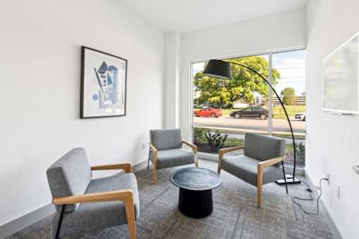 A living room with a grey sofa, a grey armchair, a black coffee table and a picture on the wall at The Point Apartments on 38th, Norfolk, Virginia