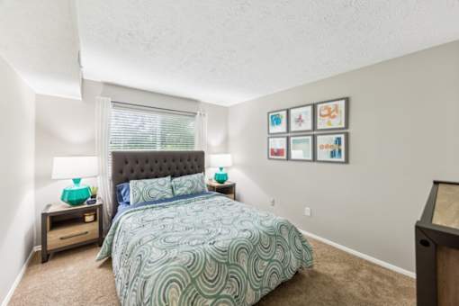 A bedroom with a bed, nightstands, and pictures on the wall at Chinoe Creek Apartments, Lexington
