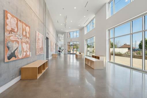 A spacious hallway with artwork on the walls and benches along the sides at South Falls Tower Apartments, Richmond
