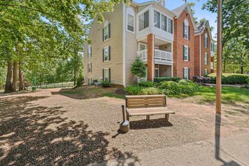 A bench sits in front of a building with a brick chimney. at The Timbers Apartments, Richmond, Virginia