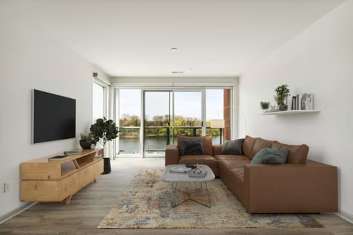 a living room with a large brown couch and a flat screen tv on the wall at The Waterford At Rocketts Landing Apartments, PRG Real Estate, Richmond, Virginia