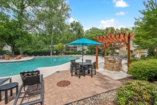 a backyard with a pool and patio with tables and umbrellas at Clarion Crossing Apartments, PRG Real Estate Management, Raleigh