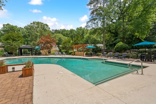 a swimming pool with trees in the background and a resort style pool at Clarion Crossing Apartments, PRG Real Estate Management, Raleigh