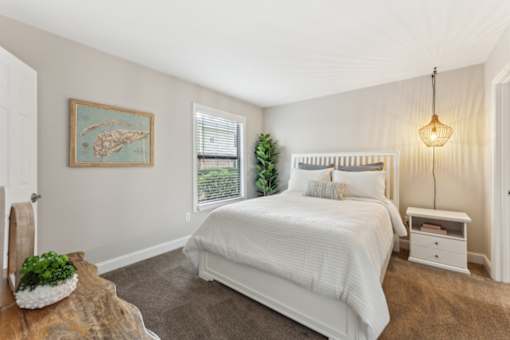 A bedroom with a large bed and a painting on the wall.