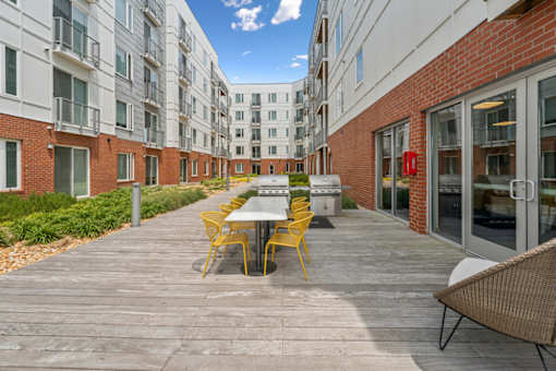 A patio with a table and chairs is surrounded by apartment buildings  at The Waterford At Rocketts Landing Apartments, PRG Real Estate, Richmond, Virginia