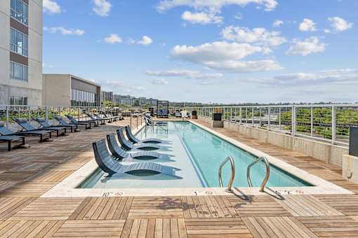 A large outdoor pool with wooden decking and lounge chairs at South Falls Tower Apartments, Richmond, VA