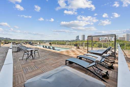 A rooftop patio with a table and chairs overlooking a city skyline at South Falls Tower Apartments, Virginia