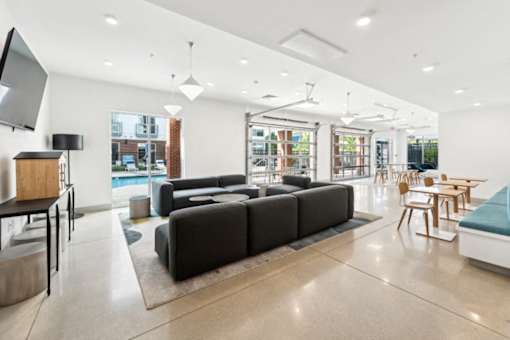 A modern living room with a black sofa and wooden chairs at The Point Apartments on 38th, Norfolk, Virginia