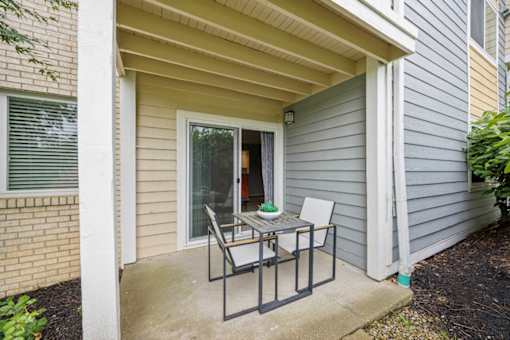 A small patio with a table and chairs is shown at Chinoe Creek Apartments, Lexington