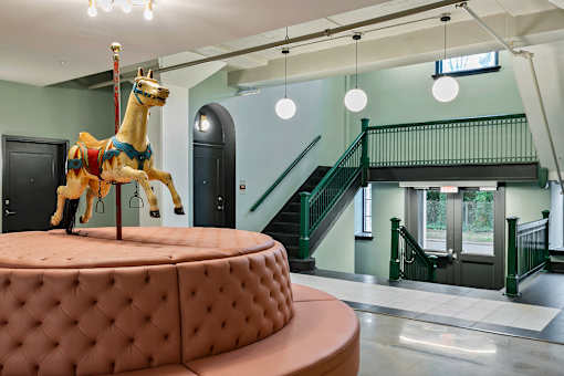 A carousel horse is on a round, tufted table in a room with a staircase at The Carousel Apartments, Richmond