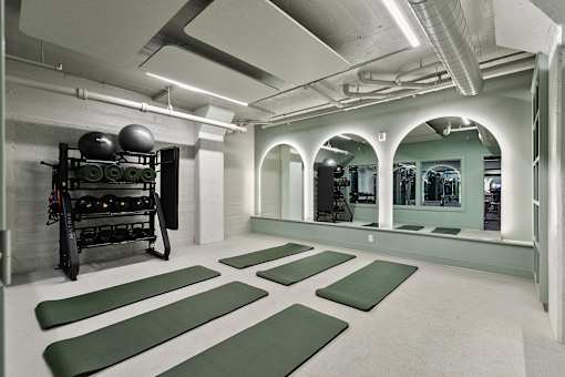 A gym with green mats and a weight rack at The Carousel Apartments, Virginia