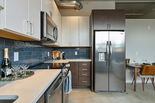 A modern kitchen with a stainless steel refrigerator and wooden chairs at The Carousel Apartments, Richmond, Virginia