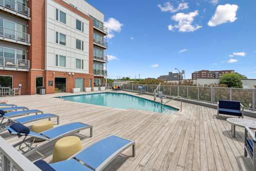 A wooden deck with a pool and sun loungers  at The Waterford At Rocketts Landing Apartments, PRG Real Estate, Richmond, Virginia