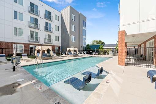 A pool with a slide and sun loungers in front of apartment buildings at The Point Apartments on 38th, Norfolk, Virginia