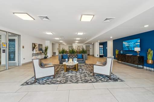 A spacious lobby with a blue accent wall and a large screen TV  at The Waterford At Rocketts Landing Apartments, PRG Real Estate, Richmond, Virginia