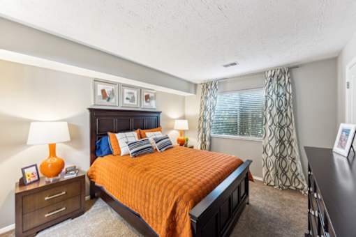 A bedroom with a bed, nightstand, and window at Chinoe Creek Apartments, Lexington 40502