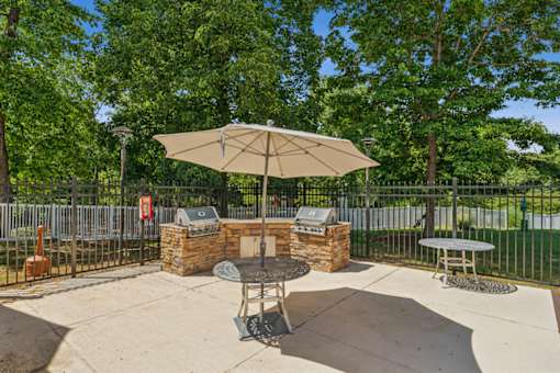 A patio with a table and chairs under an umbrella. at The Timbers Apartments, Richmond, VA, 23235