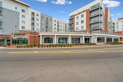 A large building with a glass entrance and a red brick base  at The Waterford At Rocketts Landing Apartments, PRG Real Estate, Richmond, Virginia