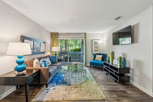 A living room with a blue rug and a glass table. at The Timbers Apartments, Virginia