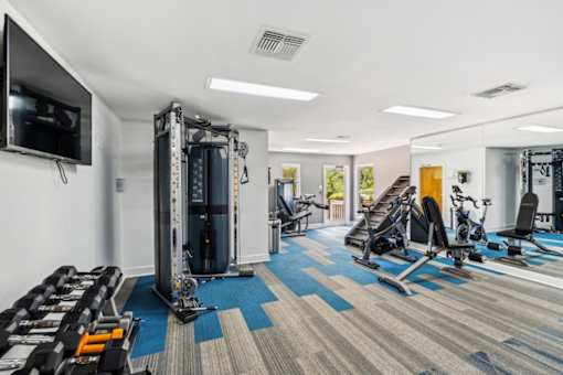 A gym with a variety of equipment including treadmills, weights, and exercise machines.