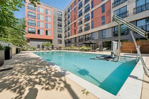 A swimming pool in front of a red and brown building.
