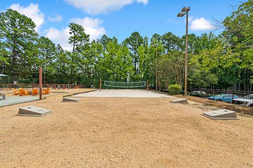 A baseball field is being prepared for a game with a green fence and trees in the background.