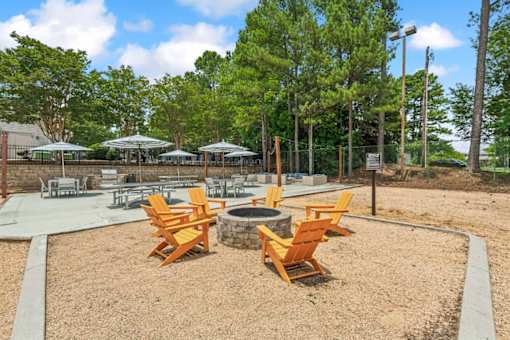 A park with a fire pit and chairs.