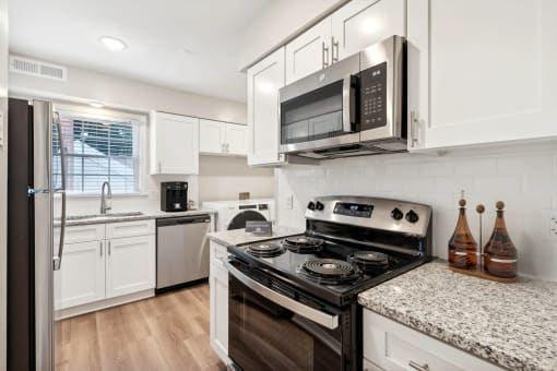 a kitchen with white cabinets and black appliances at Lake Johnson Mews, Raleigh, North Carolina