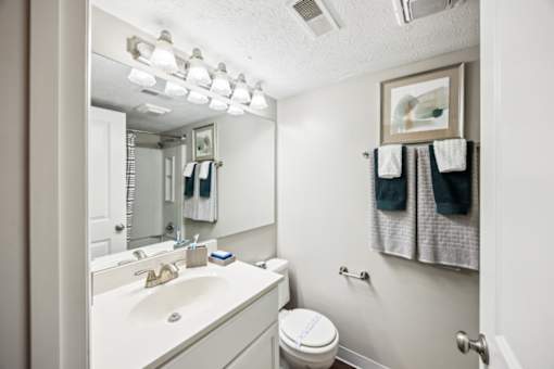 A white bathroom with a toilet, sink, and towel rack at Chinoe Creek Apartments, Lexington, Kentucky