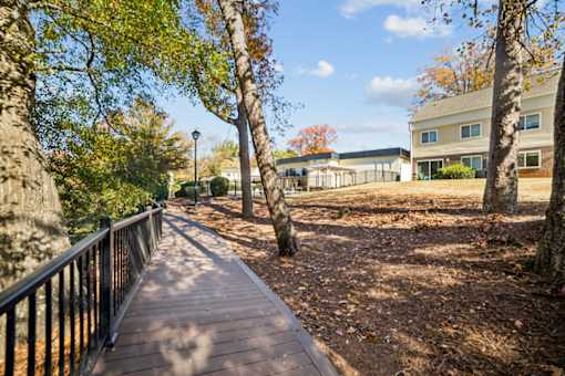 A wooden walkway with a metal railing is surrounded by trees at Lakecrest Apartments, PRG Real Estate Management, Greenville, SC, 29615