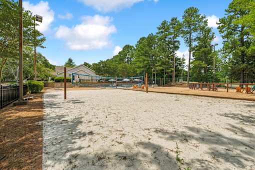 A sandy area with trees and a building in the background.
