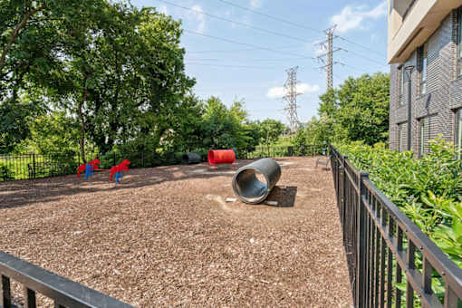 A playground with red and blue slides and a large grey tube.