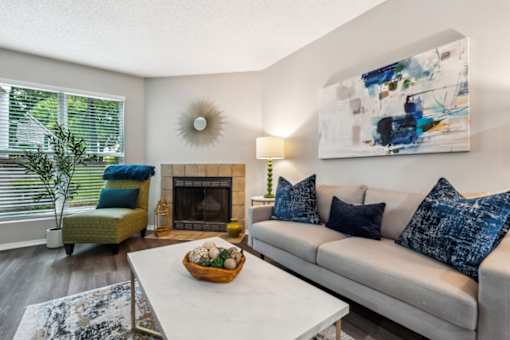 A living room with a white couch, a fireplace, and a painting on the wall.