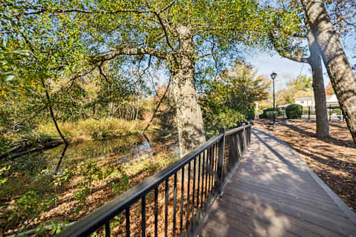 A wooden walkway with a metal railing runs through a wooded area at Lakecrest Apartments, PRG Real Estate Management, Greenville, SC, 29615